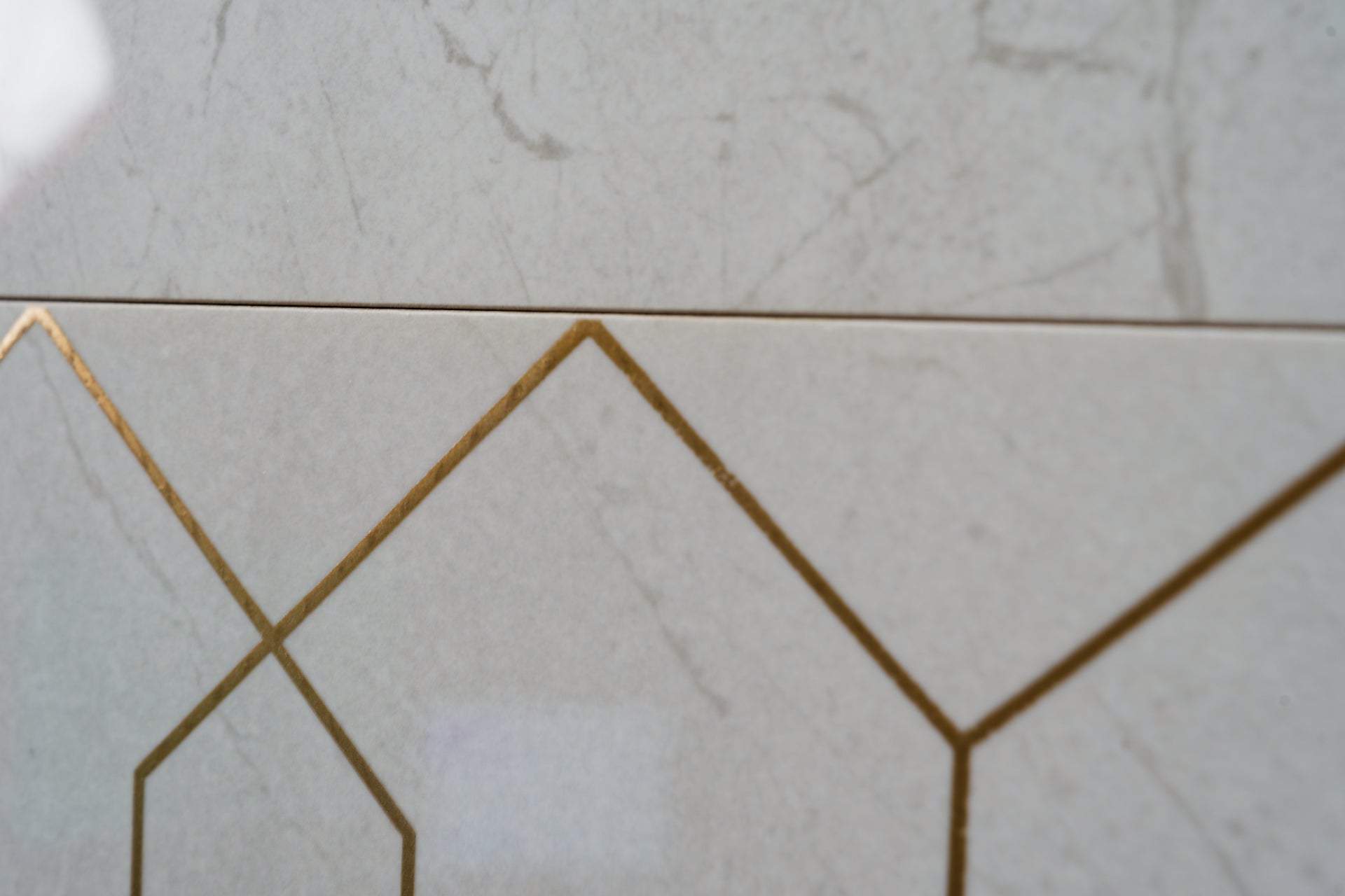 Close-up of geometric tile pattern with gold accents on a light gray background