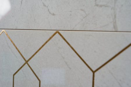 Close-up of geometric tile pattern with gold accents on a light gray background